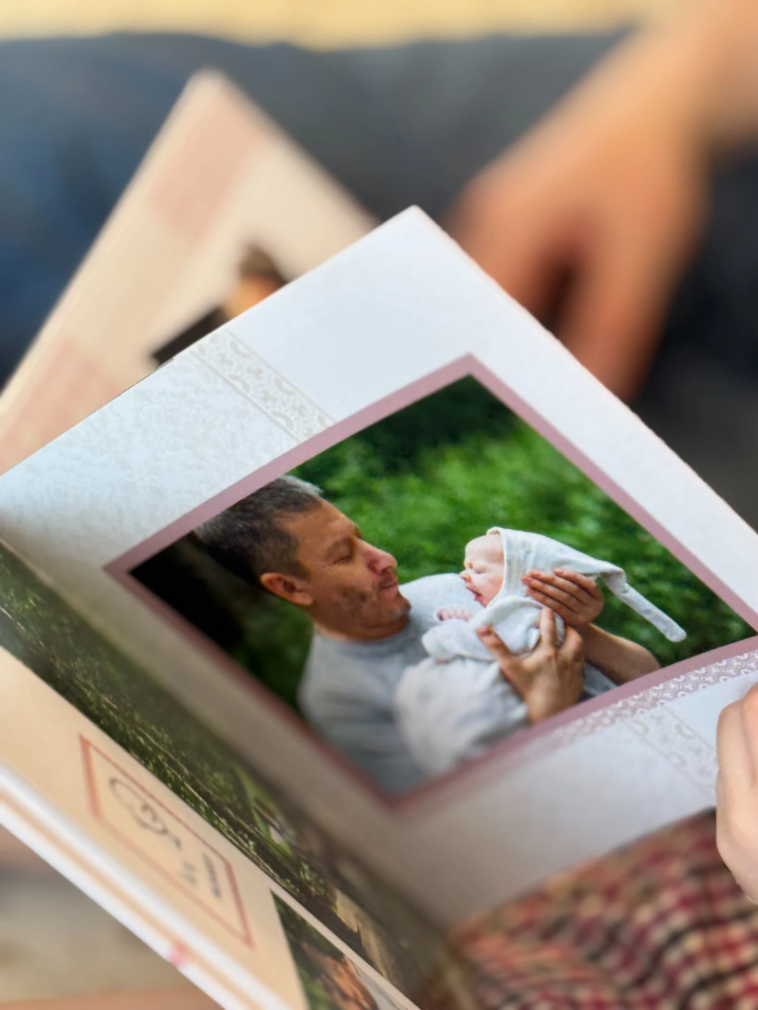 Разворот детской фотокниги — папа держит младенца на руках