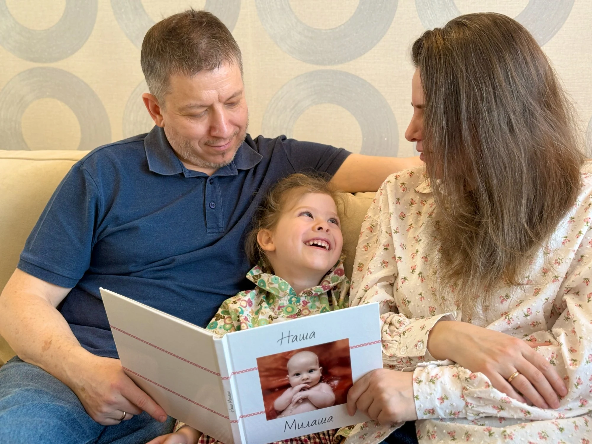 Семья листает детскую фотокнигу Милаша вместе на диване